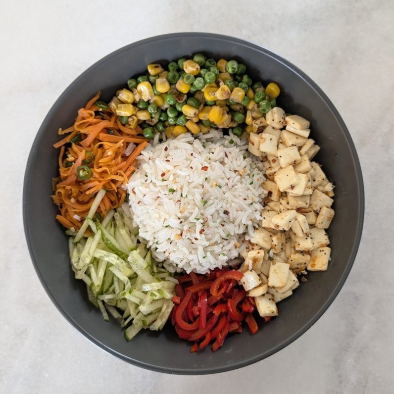 Rice bowl with paneer, carrot, cucumber, peppers, peas and corn